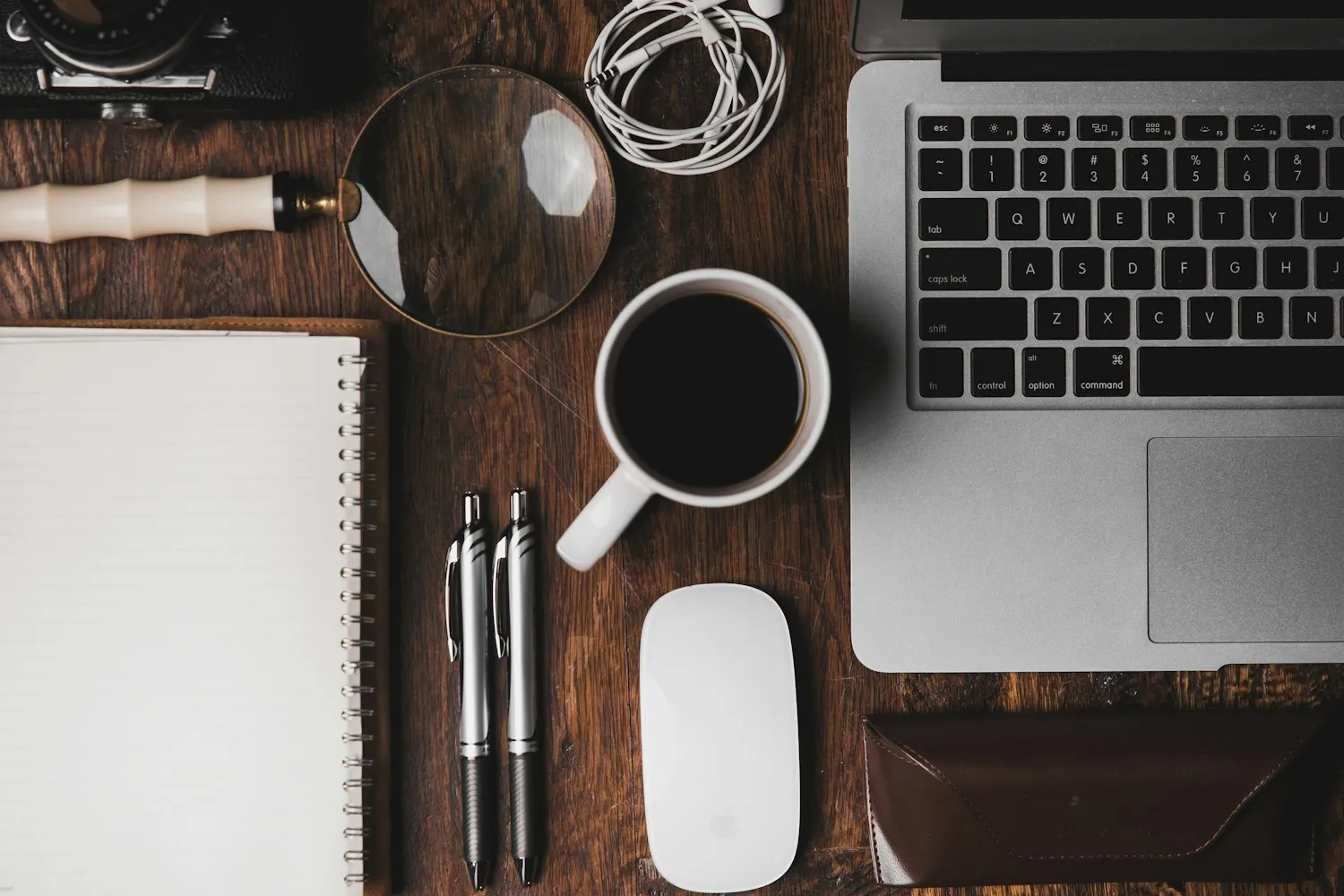 A studio desk — laptop, notebook, camera and coffee